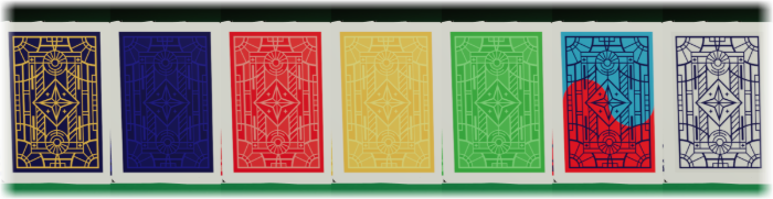 The seven card backs a table can be dealt from, standing side by side on the felt: the same stained-glass pattern printed in gold, navy, red, yellow, green, blue-and-red, and grey.